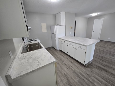 A kitchen with a white counter top and a white refrigerator.
