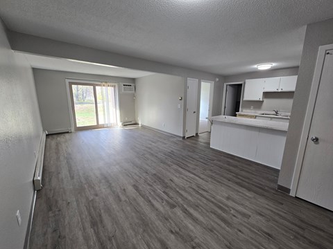 A spacious room with wooden flooring and white walls.