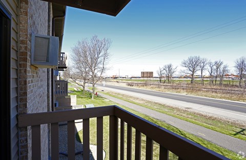A view from a balcony looking out at a road and trees.