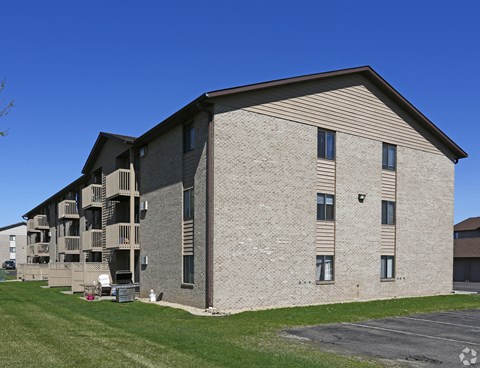 A large apartment building with a parking lot in front.