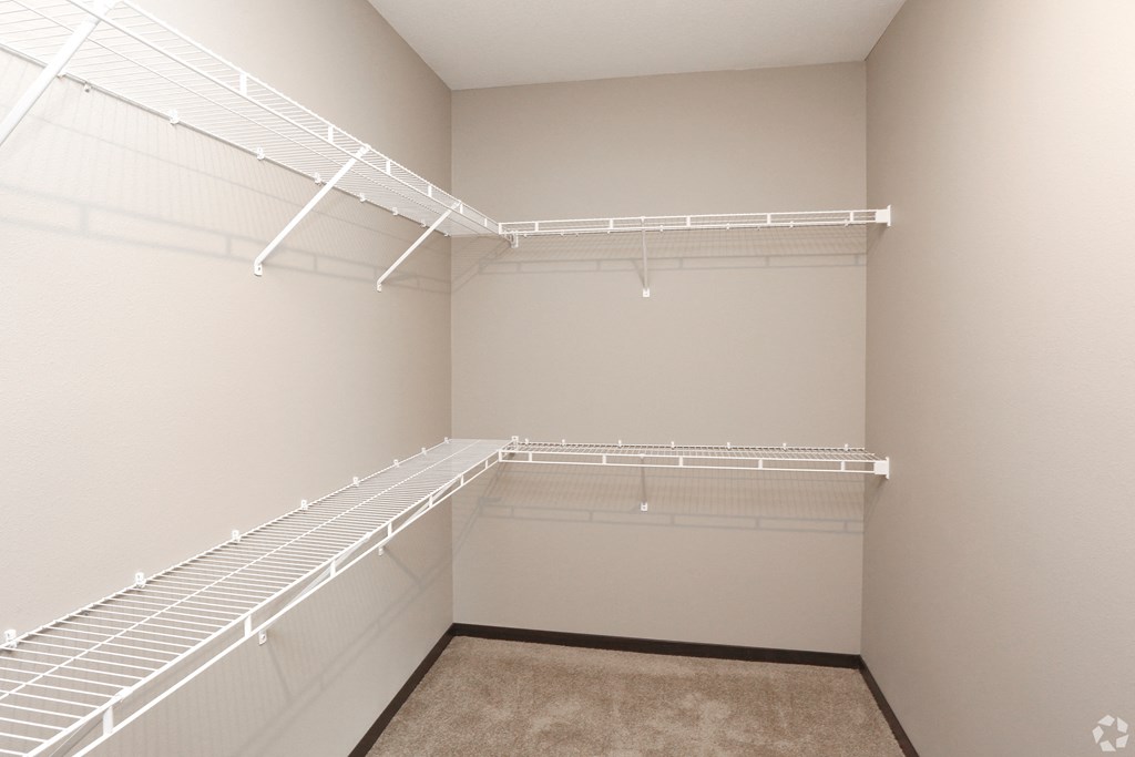 a spacious closet with white shelves and a white wall