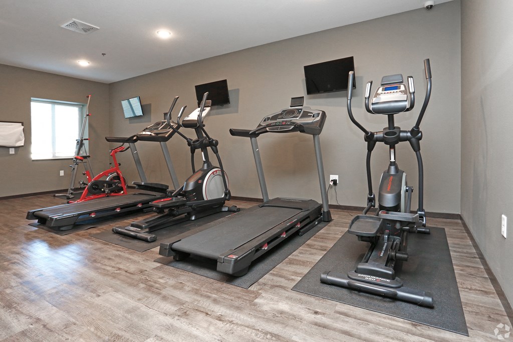 a gym with treadmills and other exercise equipment on a wooden floor