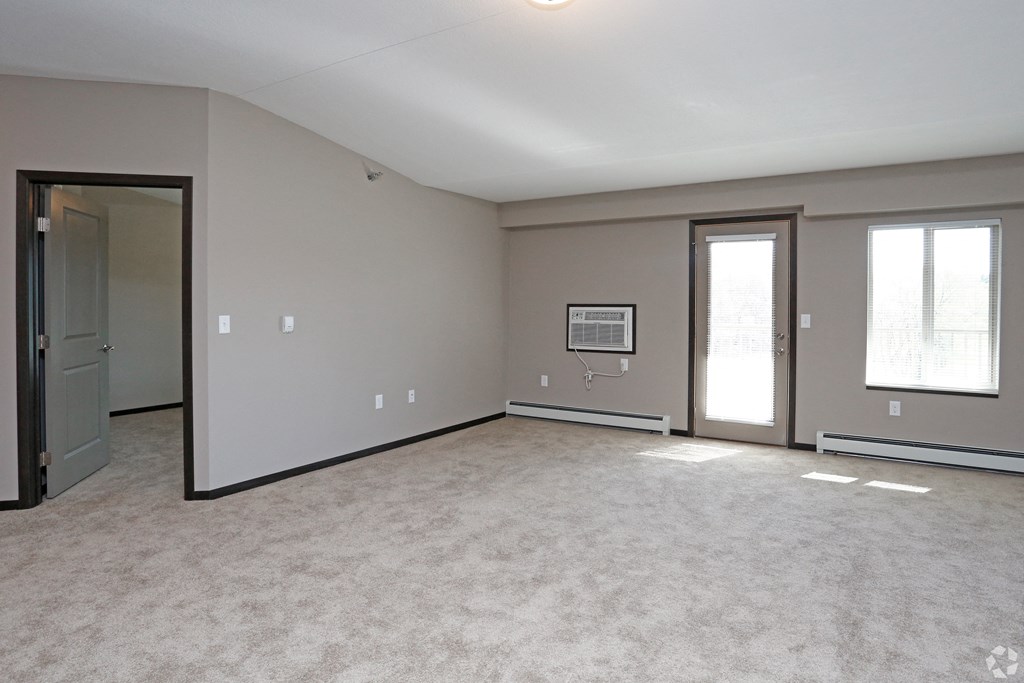 an empty living room with a door and a window