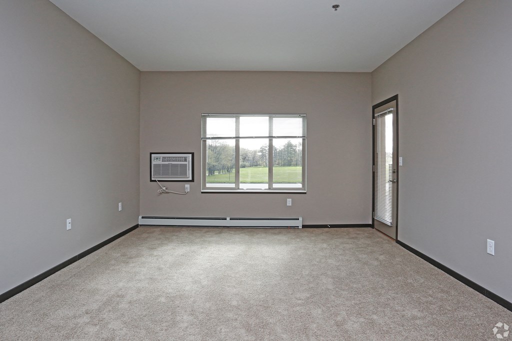 an empty living room with a window and carpet