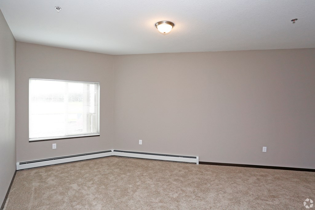 an empty living room with a window and carpet