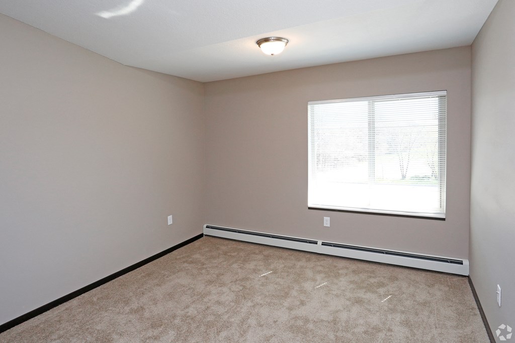 an empty living room with a window and carpet