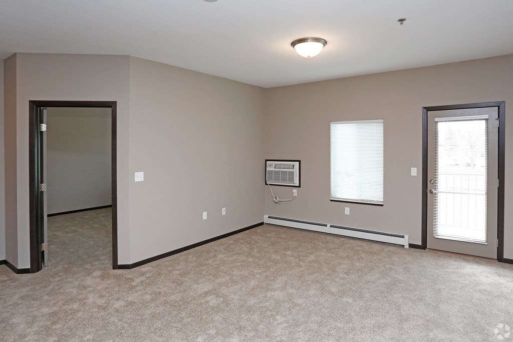an empty living room with a door to a hallway and a window
