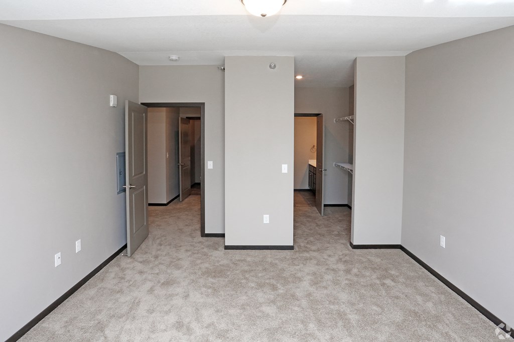 a bedroom with a carpeted floor and several closets and mirrors