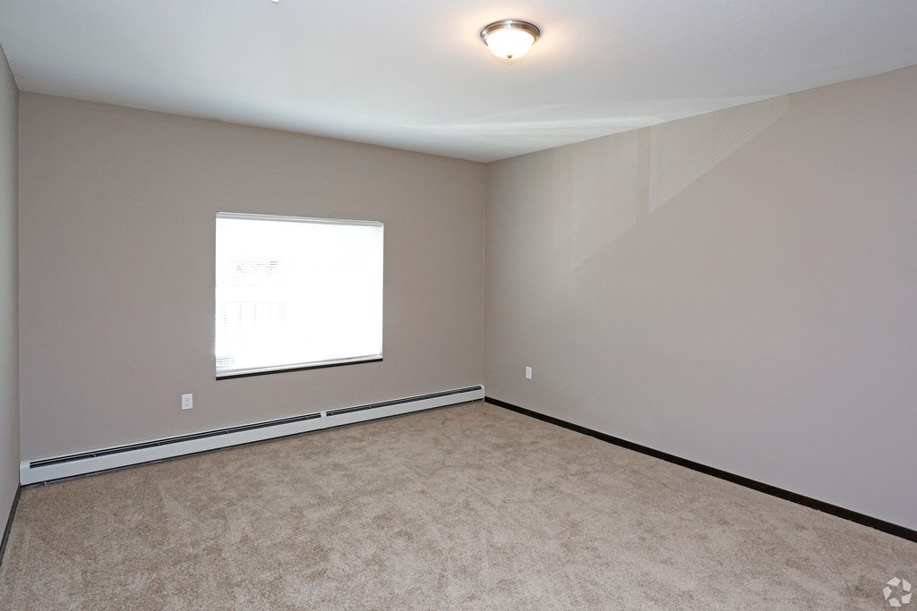 an empty room with a window and carpet