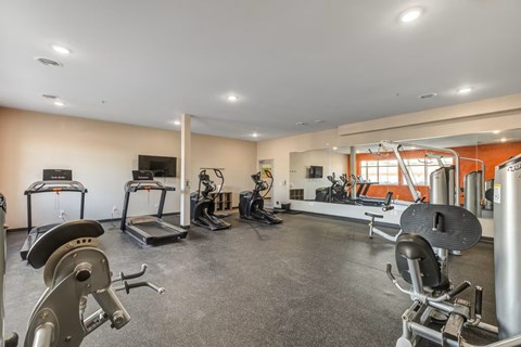 A spacious gym with a variety of equipment including treadmills, stationary bikes, and weight machines.
