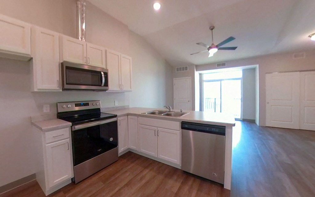 an empty kitchen with white cabinets and stainless steel appliances
