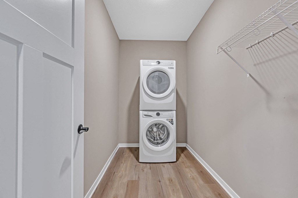 A white dryer and washer are stacked on top of each other in a small laundry room.