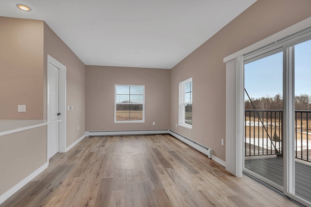 A room with wooden floors and a sliding glass door leading to a balcony.