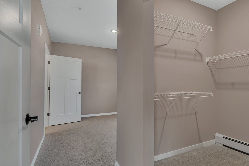 A room with a white door and a wall-mounted closet with shelves.