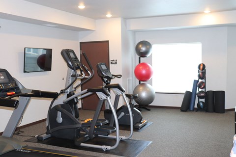 a gym with two exercise machines and a yoga ball on the floor