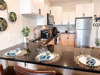 a kitchen with white cabinets and a black counter top