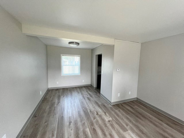 an empty living room with wood floors and a window