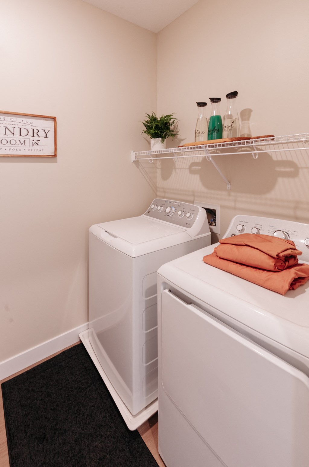 a washer and dryer in a small laundry room with a shelf above them