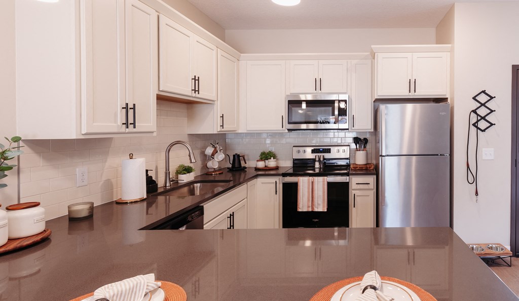 a modern kitchen with stainless steel appliances and white cabinets