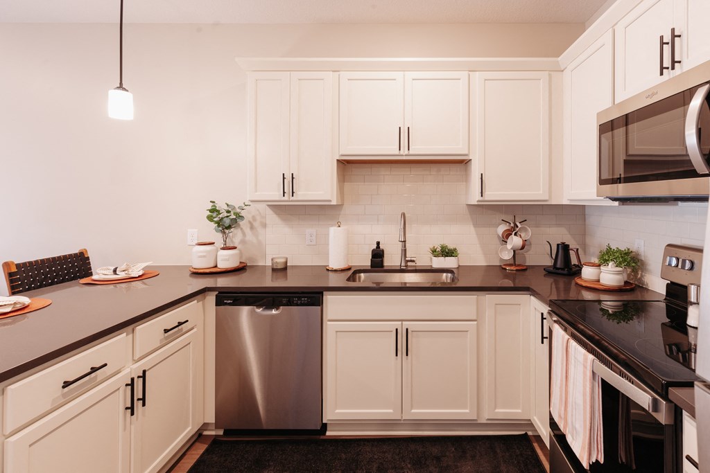 a kitchen with white cabinets and a black counter top