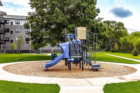 A playground with a blue slide and a yellow sign.