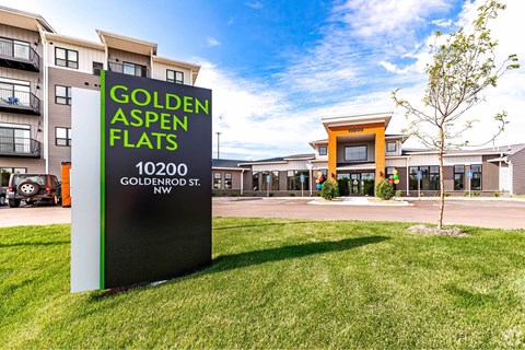 A sign for Golden Aspen Flats is in the foreground of a grassy area.