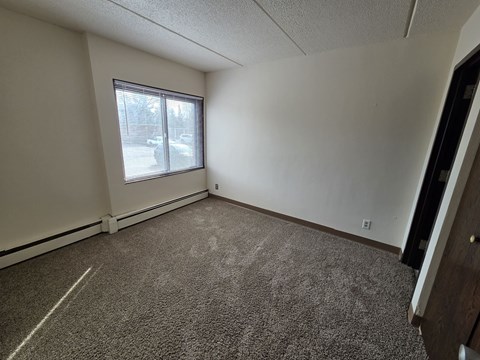 A room with a carpeted floor and a window with blinds.