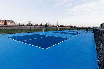 a tennis court with blue surface on a sunny day