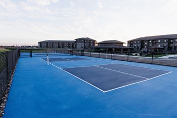 a tennis court with apartments in the background