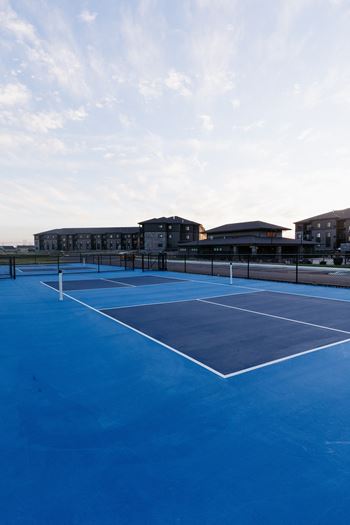 a blue tennis court with buildings in the background