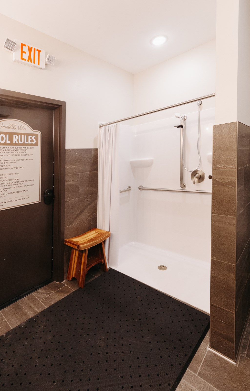 a small bathroom with a shower and a wooden stool