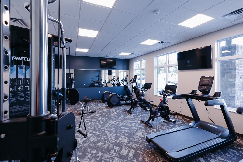 a gym with various exercise machines and a tv