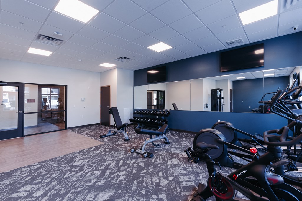 a workout room with bikes and chairs and a wall mounted tv