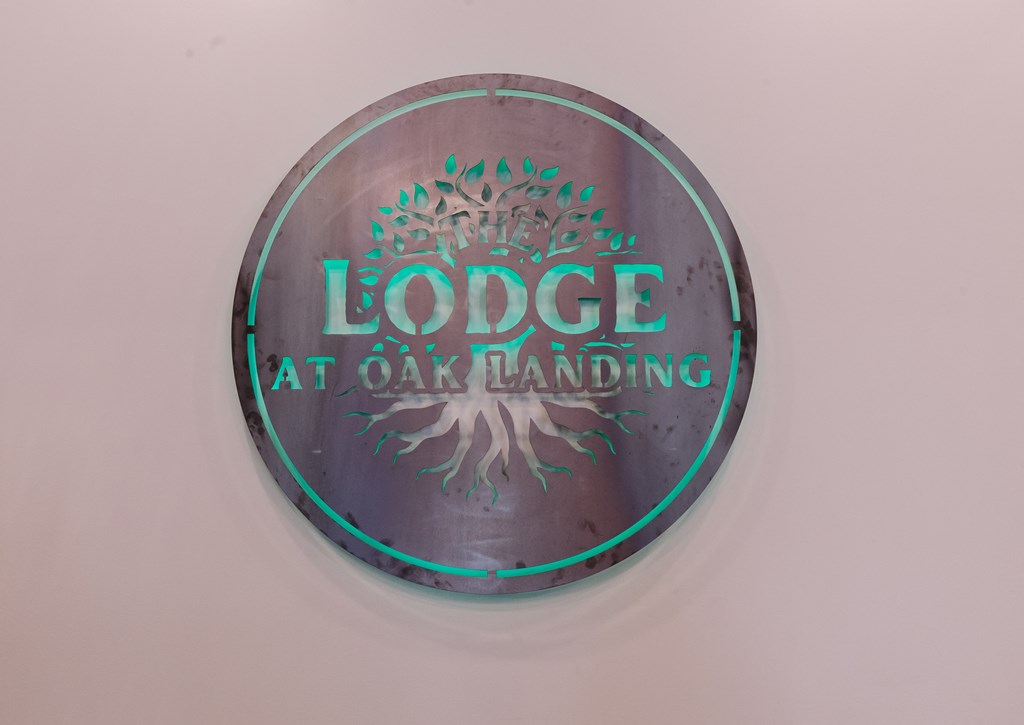 a metal button with a tree and the words lodges at oak landing on it