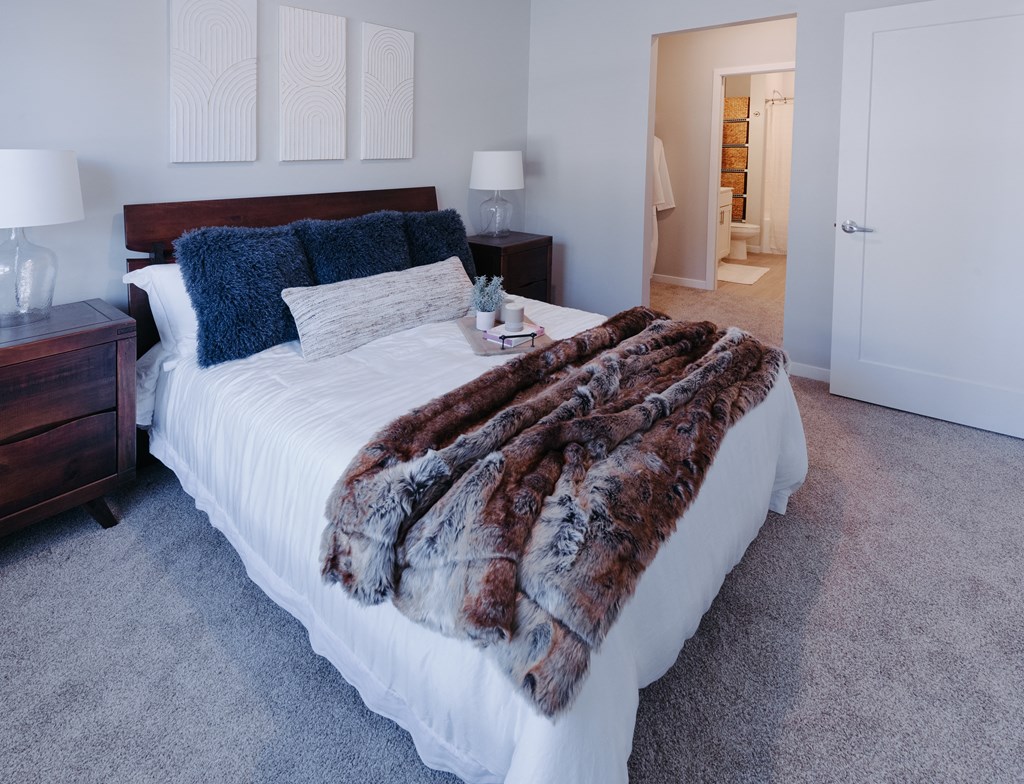 a bedroom with a white bed and a furry blanket