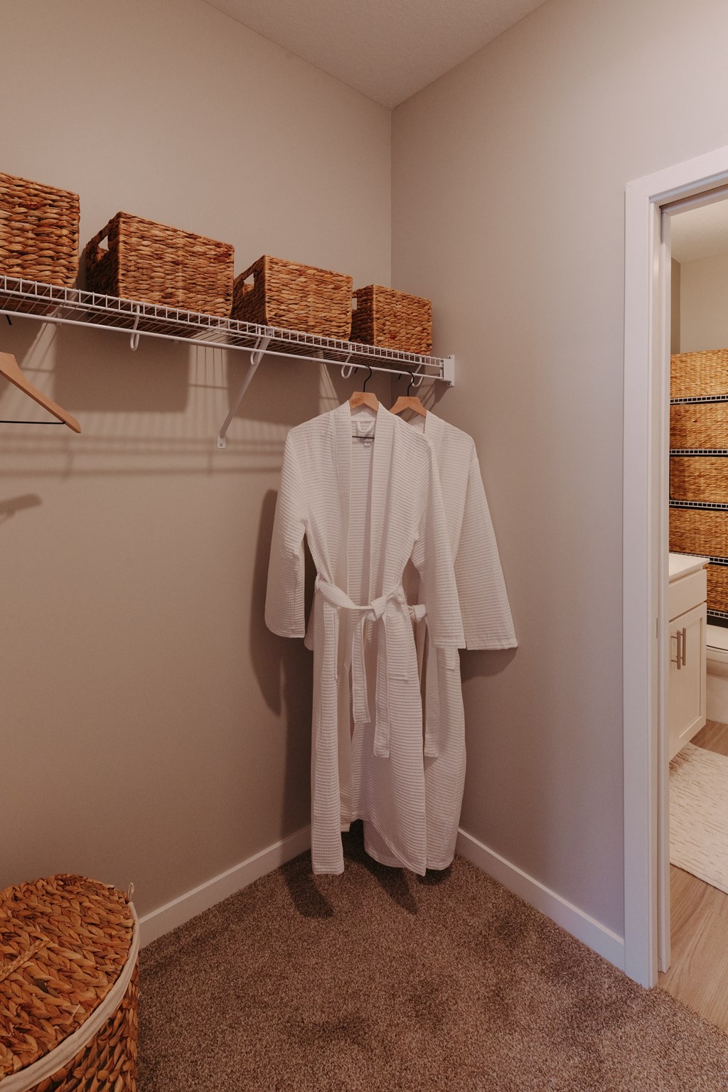 a white robe hangs on a rack in a closet