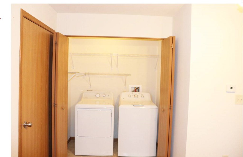 Two white washing machines in a small laundry room.