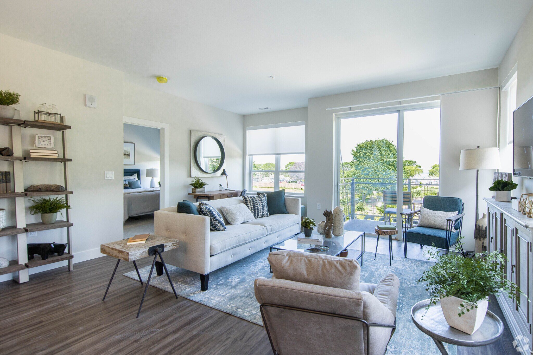 A living room with a couch, a chair, and a table with a plant on it.