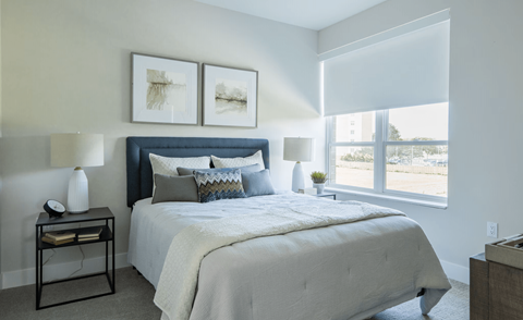 A bedroom with a large bed and two pictures on the wall.