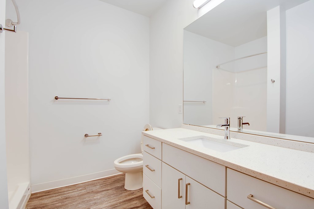 A white bathroom with a toilet, sink, and mirror.