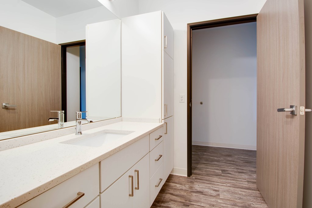 A bathroom with a sink, mirror, and cabinets.