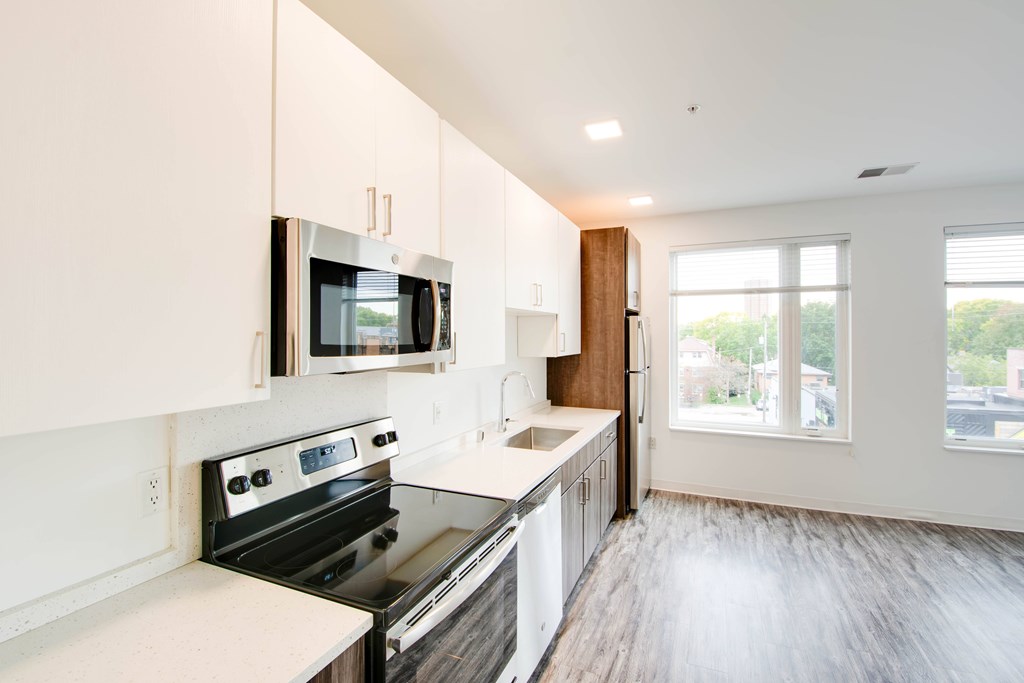 A modern kitchen with white cabinets and a black stove top oven.