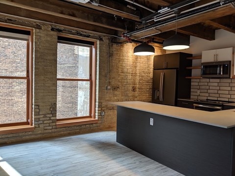 A kitchen with a black counter and a brick wall.