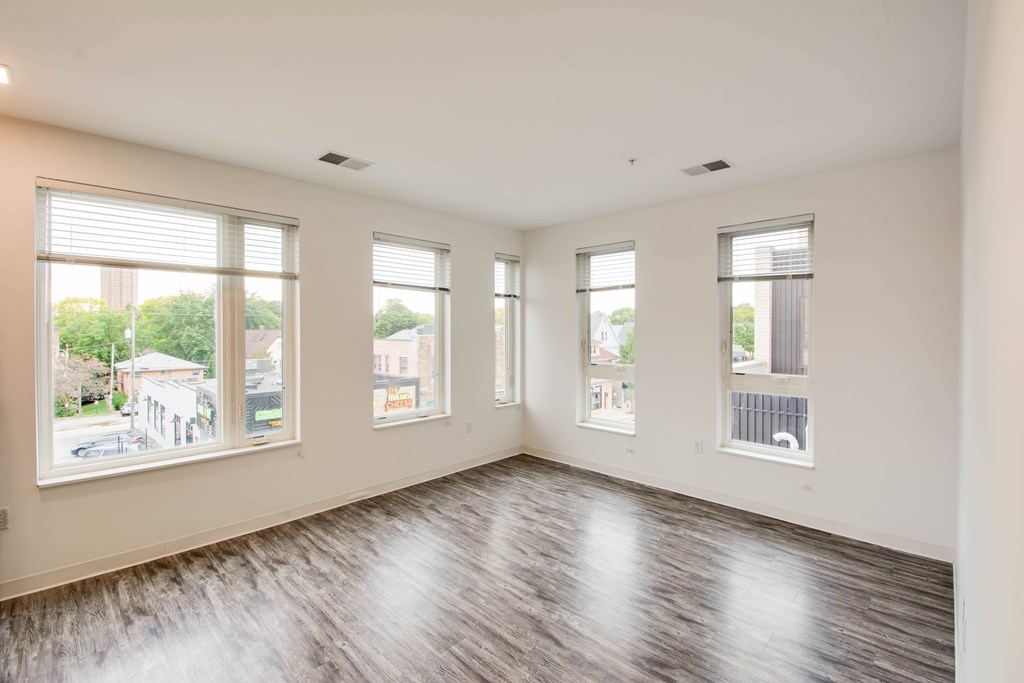Empty room with wooden floors and large windows.