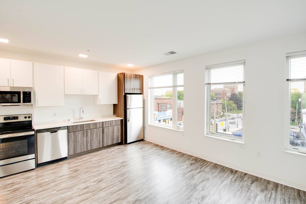 A kitchen with white cabinets and a wooden floor.