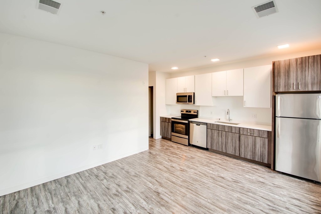 A kitchen with a refrigerator, microwave, oven, and sink.