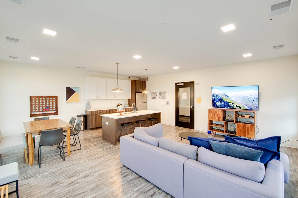 A modern living room with a grey sofa and a wooden dining table.