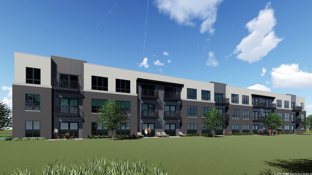 A modern apartment building with multiple balconies and a grassy area in front.