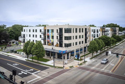 A street view of a city intersection with a white building on the corner.