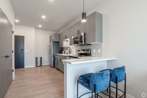 A kitchen with a white counter and blue chairs.